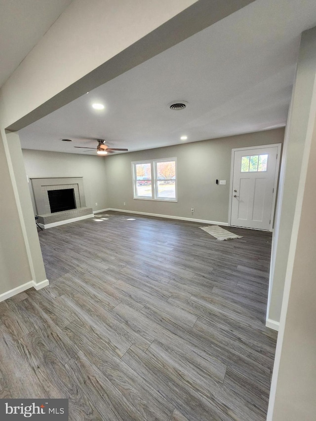 unfurnished living room with a brick fireplace, ceiling fan, plenty of natural light, and hardwood / wood-style flooring