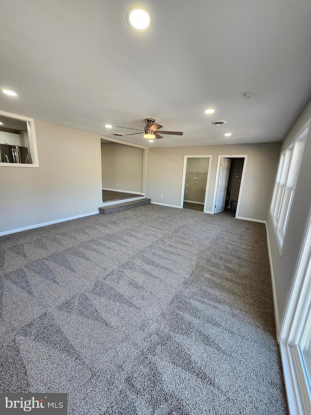 unfurnished living room with dark colored carpet and ceiling fan