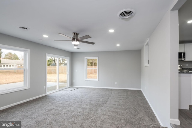 unfurnished living room with ceiling fan and dark carpet