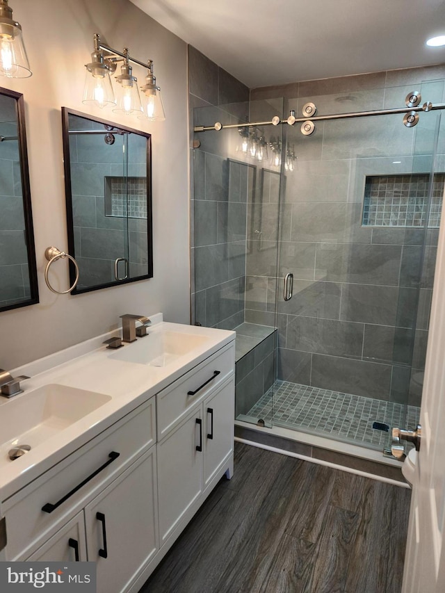 bathroom with hardwood / wood-style floors, vanity, and a shower with door