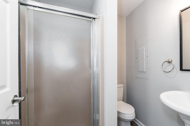 bathroom with toilet, a shower with shower door, sink, and electric panel