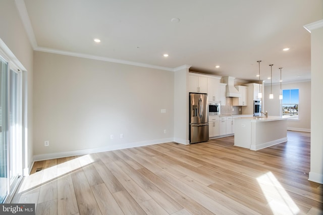 kitchen featuring decorative light fixtures, light hardwood / wood-style floors, stainless steel appliances, and a kitchen island with sink