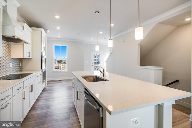 kitchen featuring custom exhaust hood, an island with sink, appliances with stainless steel finishes, decorative light fixtures, and white cabinetry