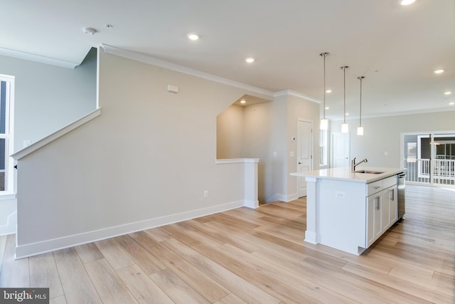 kitchen with white cabinetry, sink, an island with sink, light hardwood / wood-style floors, and ornamental molding