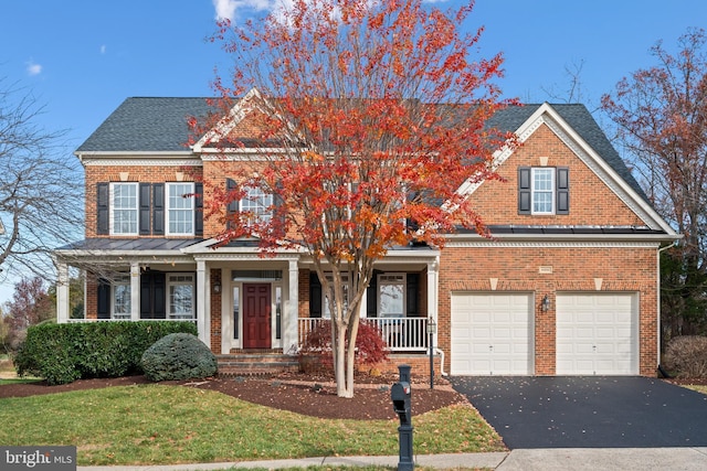 view of front of house featuring covered porch, a garage, and a front yard