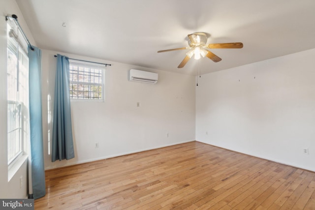 unfurnished room featuring light wood-type flooring, an AC wall unit, and ceiling fan