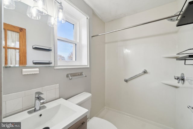 bathroom featuring tasteful backsplash, walk in shower, vanity, and toilet