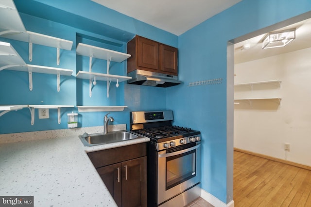 kitchen featuring dark brown cabinetry, stainless steel gas stove, light hardwood / wood-style floors, and sink