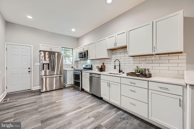 kitchen with white cabinets, stainless steel appliances, light hardwood / wood-style flooring, and sink