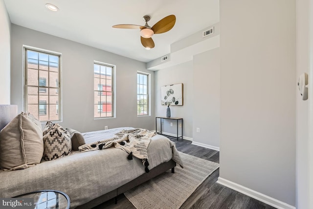 bedroom with multiple windows, ceiling fan, and dark wood-type flooring