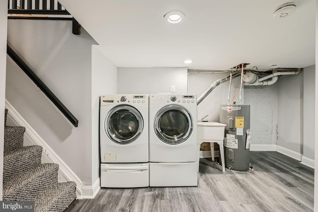 laundry area featuring washing machine and clothes dryer, wood-type flooring, and water heater