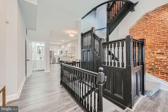 stairway featuring wood-type flooring and brick wall