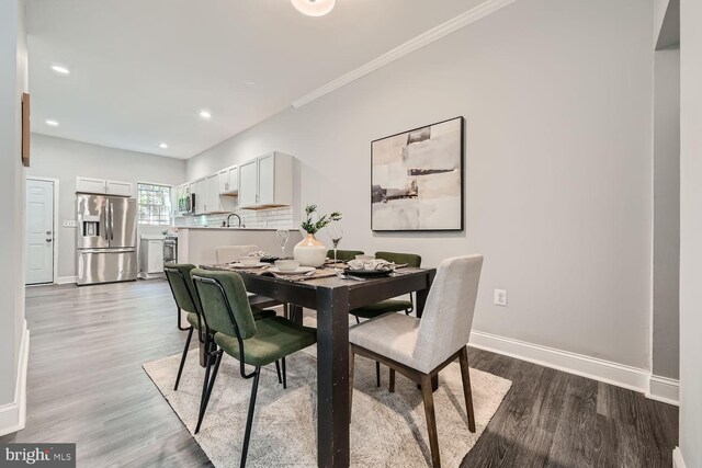 dining area with sink, light hardwood / wood-style flooring, and ornamental molding