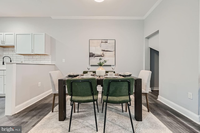 dining area featuring sink, dark hardwood / wood-style flooring, and crown molding