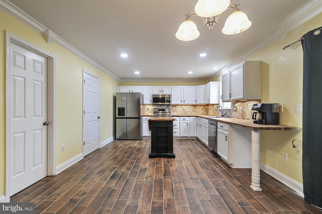 kitchen featuring dark wood-type flooring, hanging light fixtures, appliances with stainless steel finishes, butcher block countertops, and white cabinetry