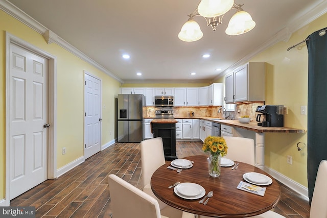 kitchen with white cabinetry, sink, hanging light fixtures, wooden counters, and appliances with stainless steel finishes