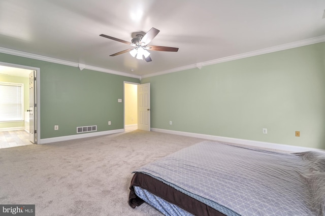 carpeted bedroom with ceiling fan, ornamental molding, and ensuite bath