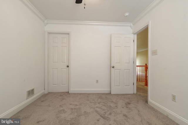 spare room with light colored carpet, ceiling fan, and crown molding