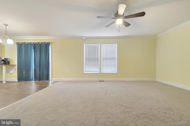 spare room featuring crown molding, hardwood / wood-style floors, and ceiling fan with notable chandelier