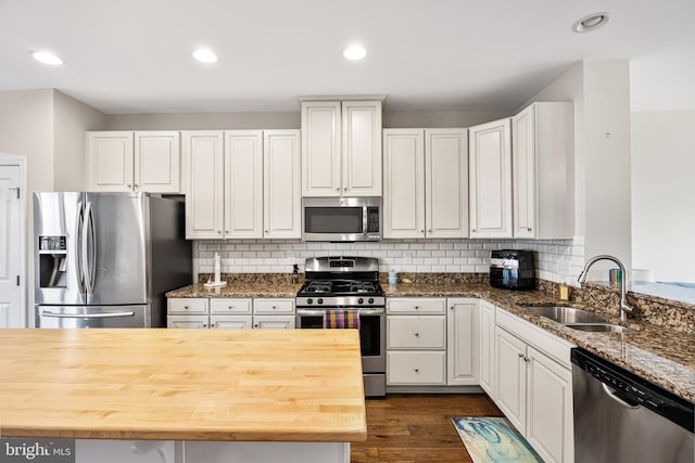 kitchen with wood counters, appliances with stainless steel finishes, dark wood-style flooring, white cabinetry, and a sink