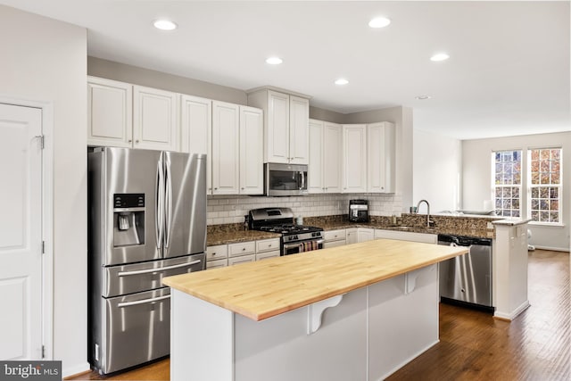 kitchen with a peninsula, a kitchen island, a breakfast bar area, and stainless steel appliances