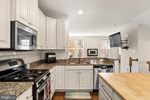 kitchen featuring stainless steel appliances, a peninsula, and white cabinets