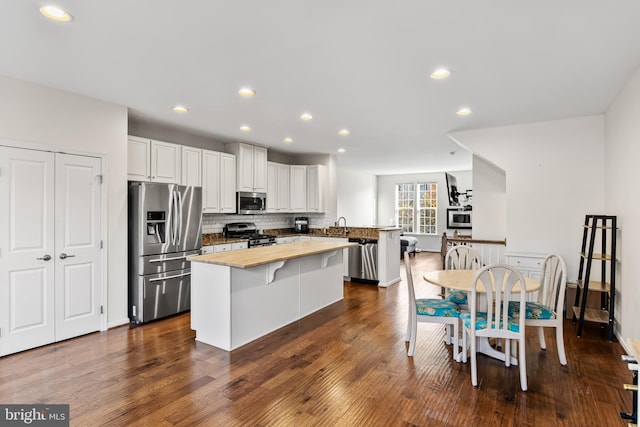 kitchen featuring butcher block counters, decorative backsplash, appliances with stainless steel finishes, dark wood-type flooring, and white cabinetry