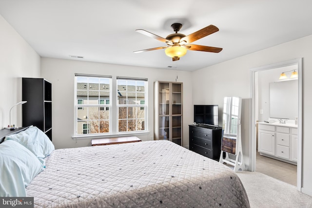 bedroom featuring light carpet, ensuite bath, visible vents, and ceiling fan