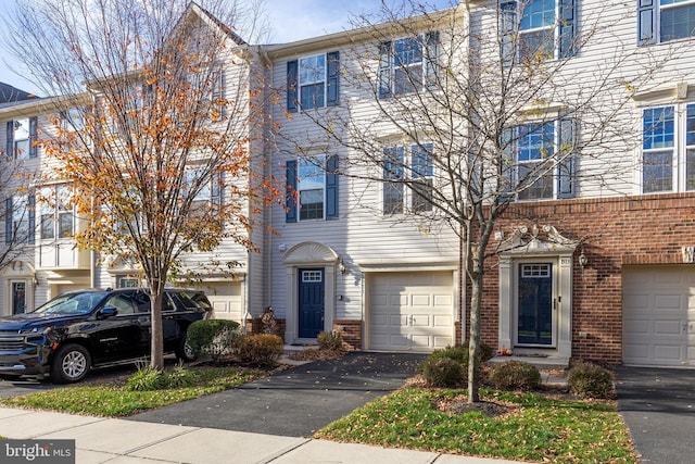 townhome / multi-family property with aphalt driveway, brick siding, and an attached garage