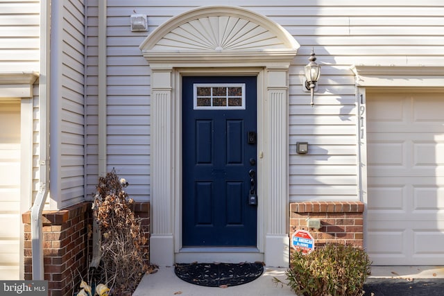 view of exterior entry with a garage and brick siding