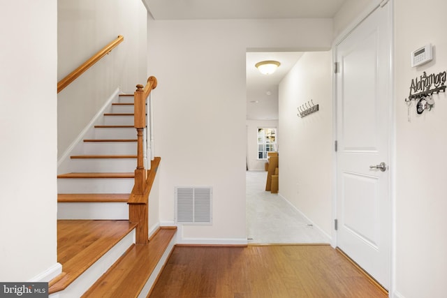 stairway featuring baseboards, visible vents, and wood finished floors