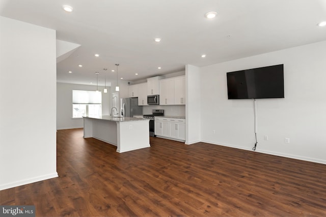 kitchen featuring dark wood-type flooring, white cabinets, sink, an island with sink, and stainless steel appliances