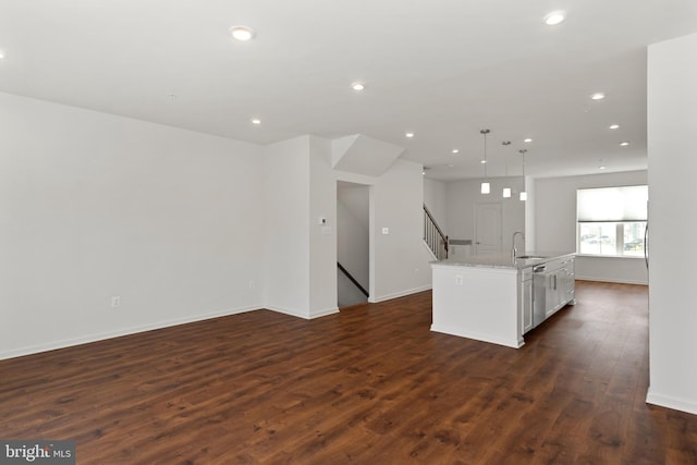 kitchen with a center island with sink, sink, dark hardwood / wood-style floors, decorative light fixtures, and white cabinetry