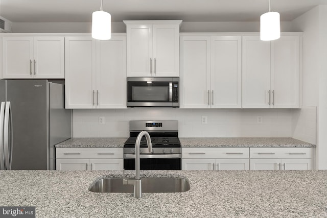 kitchen with white cabinetry, hanging light fixtures, and stainless steel appliances