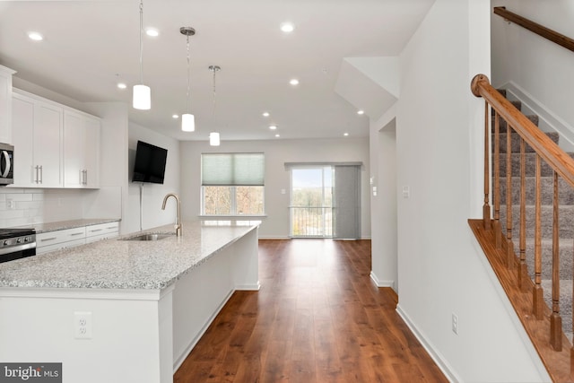 kitchen featuring sink, white cabinetry, an island with sink, and dark wood-type flooring