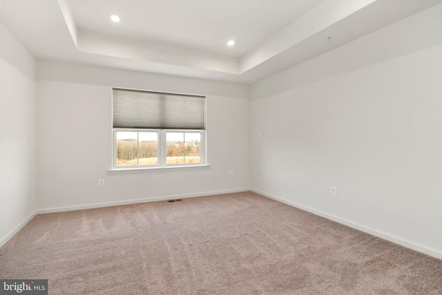 carpeted empty room featuring a tray ceiling