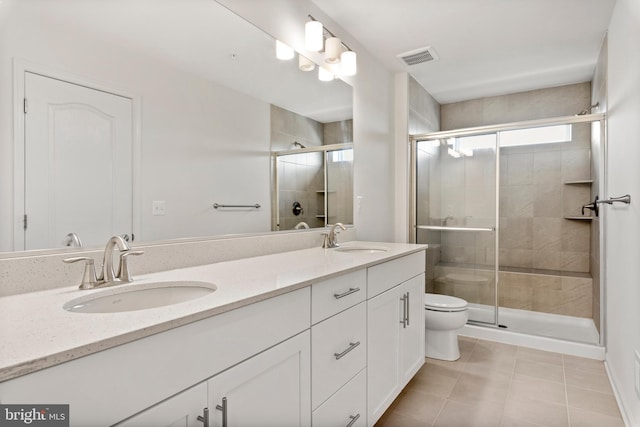 bathroom featuring tile patterned floors, a shower with door, vanity, and toilet