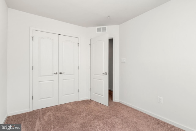 unfurnished bedroom with light carpet and a closet