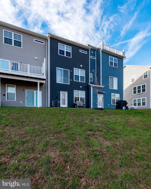 back of property featuring a lawn and central air condition unit