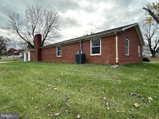 view of side of home featuring a lawn and cooling unit