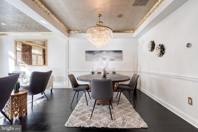 dining area with a raised ceiling, ornamental molding, dark hardwood / wood-style floors, and an inviting chandelier