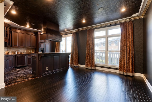 kitchen with custom exhaust hood, ornamental molding, dark wood-type flooring, and dark brown cabinetry