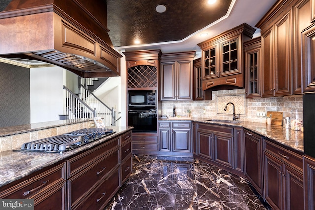 kitchen with light stone countertops, sink, custom range hood, and black appliances