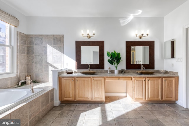 bathroom featuring tile patterned flooring, vanity, and tiled bath