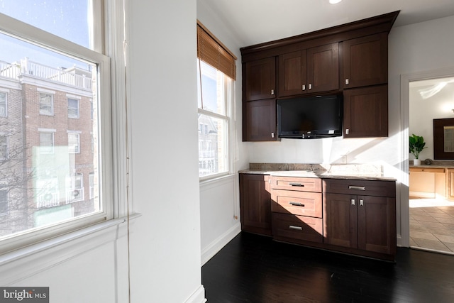 kitchen with dark hardwood / wood-style flooring, light stone countertops, and dark brown cabinets