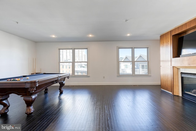 rec room featuring a tiled fireplace, a wealth of natural light, and dark hardwood / wood-style floors