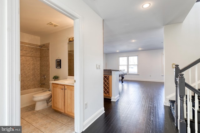 full bathroom featuring tiled shower / bath combo, vanity, wood-type flooring, and toilet