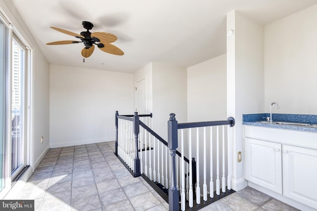 stairway featuring ceiling fan and sink