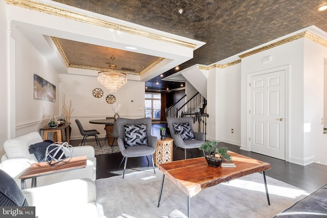 living room featuring a tray ceiling, hardwood / wood-style floors, crown molding, and a chandelier