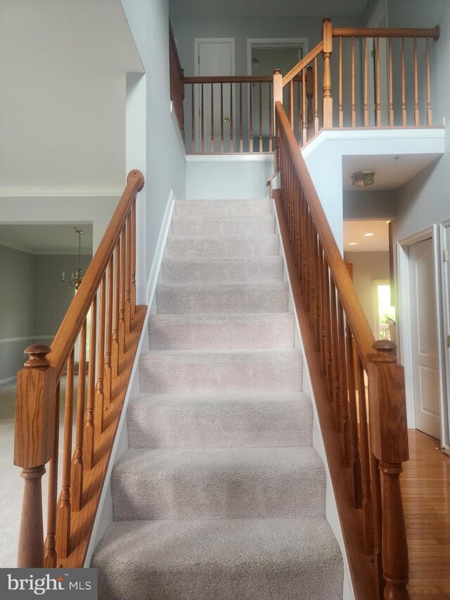 staircase with wood-type flooring and a notable chandelier